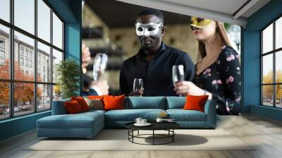 Masquerade party. Beautiful women and men wearing fantasy mask. Company employee enjoy drinking in mask party  together indoors celebration Wall mural